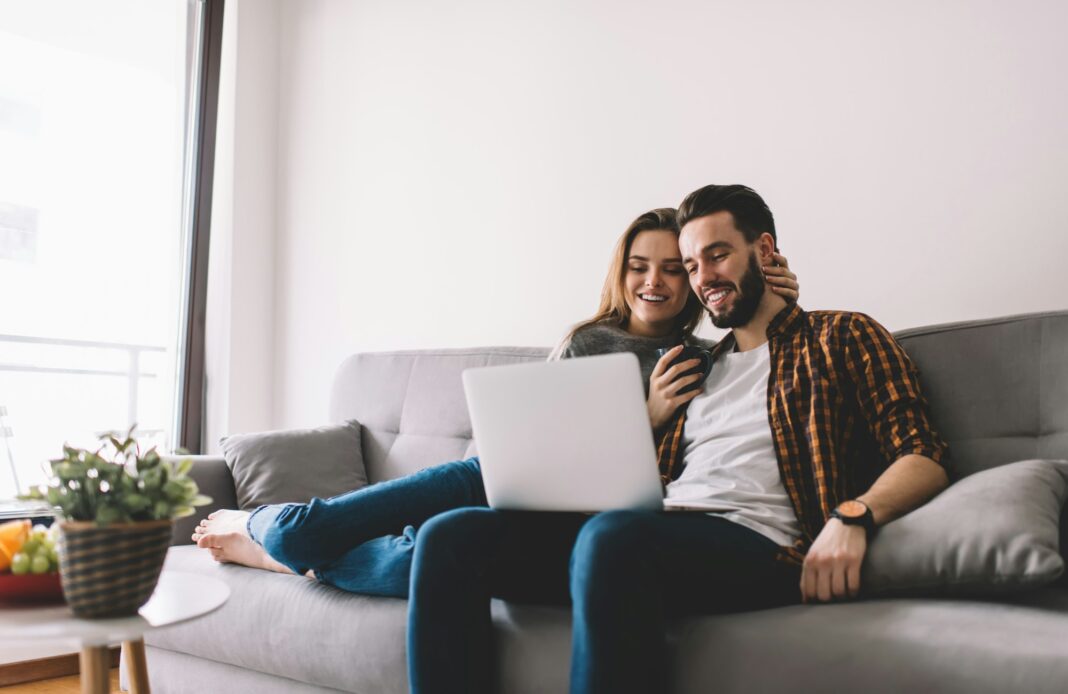 Happy couple watching film on laptop