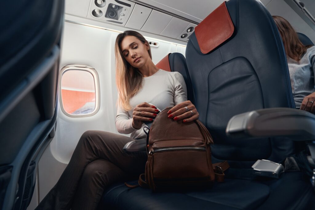 Woman on aircraft hiding smartphone into her bag